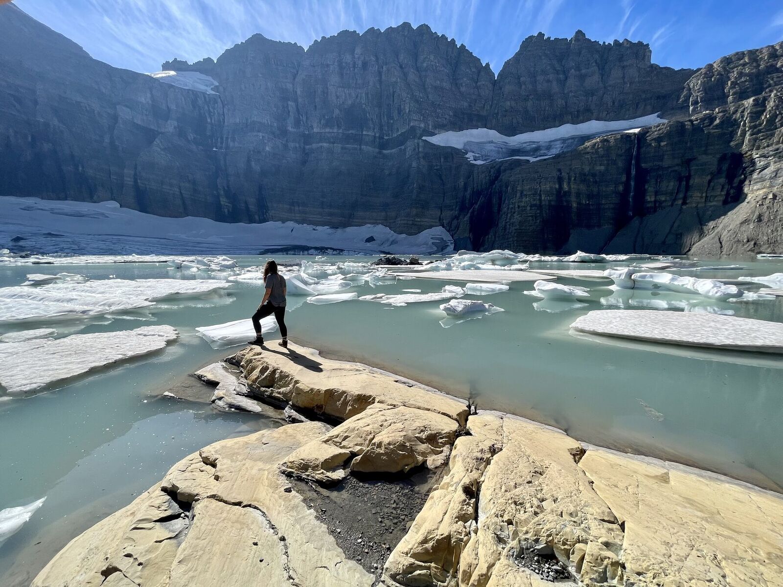 Standing at the edge of Grinnell Glacier above a turquoise lake