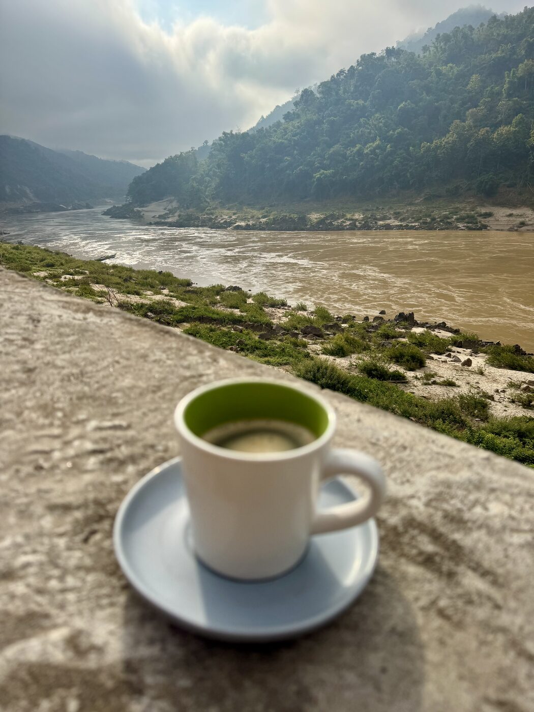 A cup of coffee on a ledge above the Mekong river