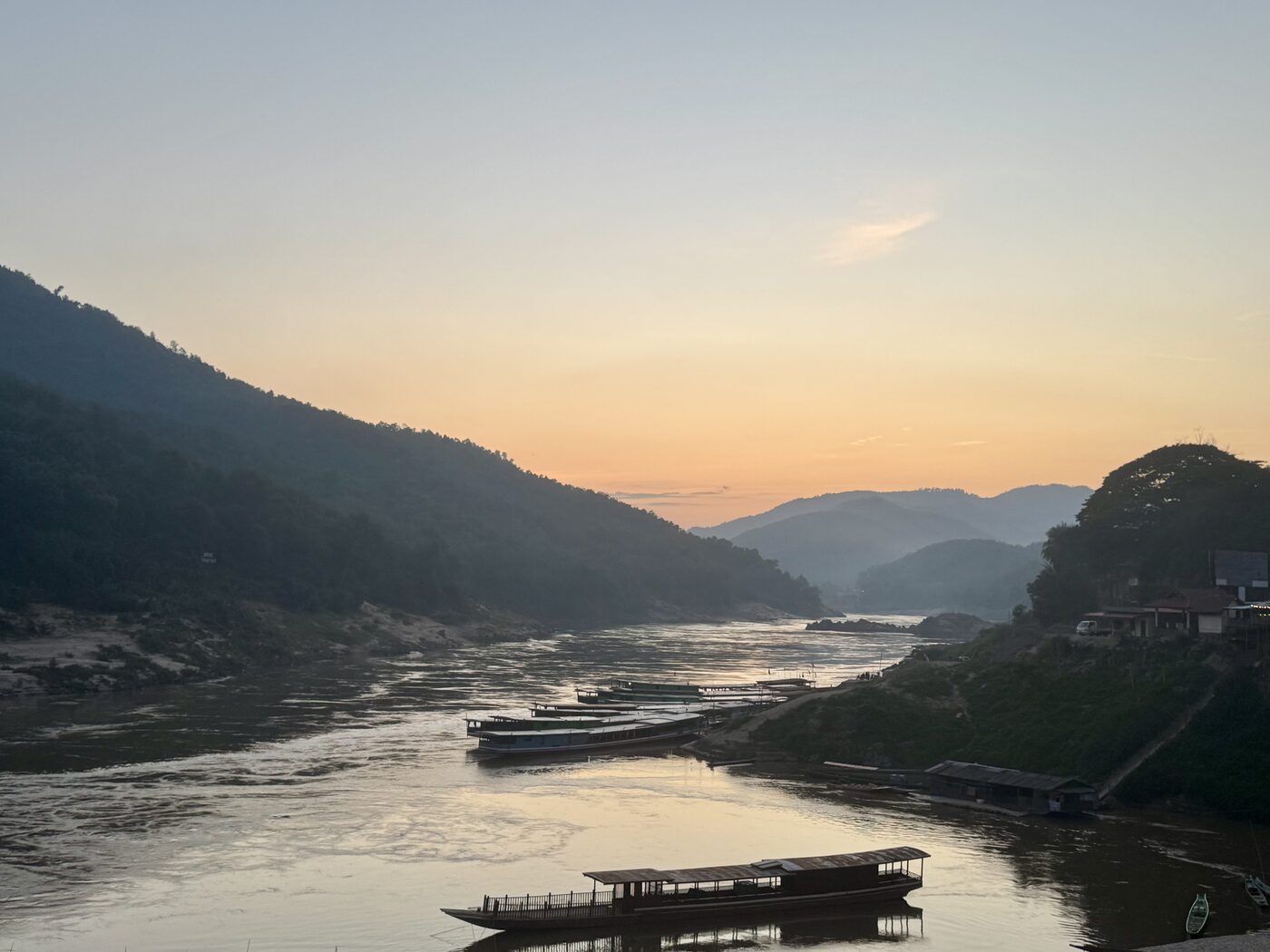 Slow boats on the Mekong at dusk, hills behind