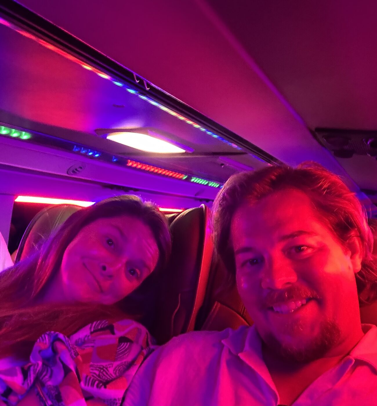 Jesse and Karlee in their bunk on the overnight bus, lit pink