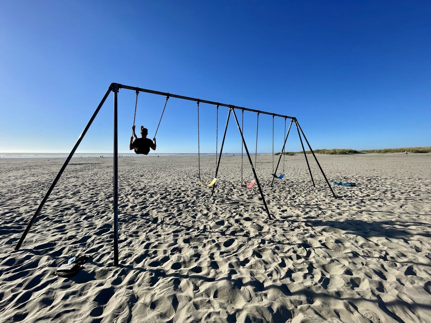 Someone on a swing set on the sand at Seaside