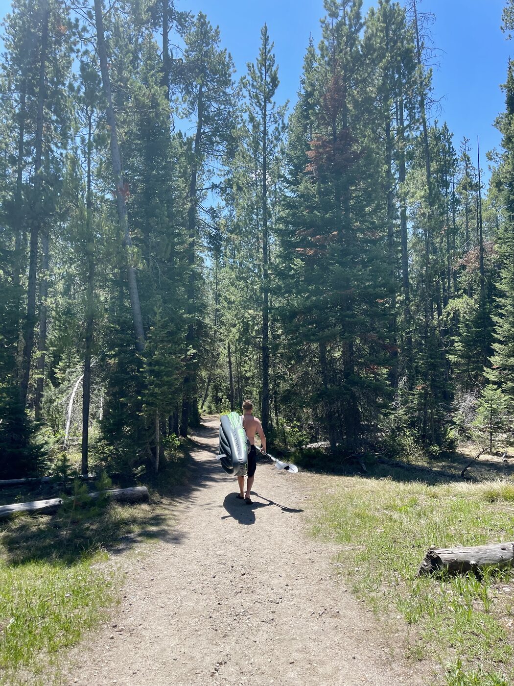 Carrying an inflatable kayak along a forest trail between lakes