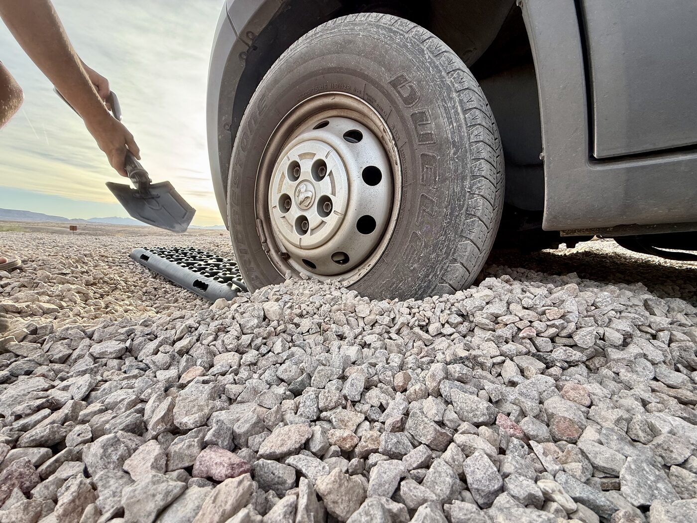 Digging out a van tire with traction boards on loose gravel